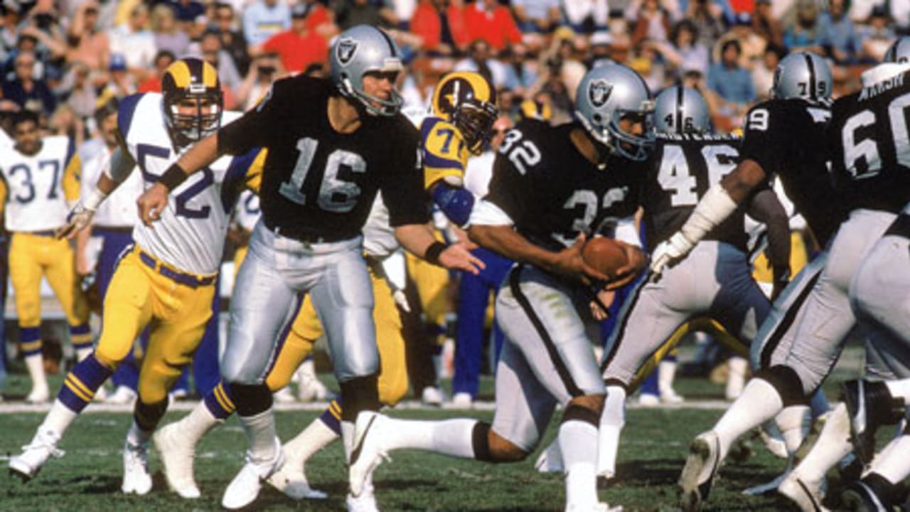 Los Angeles Raiders running back Marcus Allen, who was named Most Valuable  Player, gives the number one sign and holds up the Super Bowl Trophy in the  locker room at Tampa Stadium