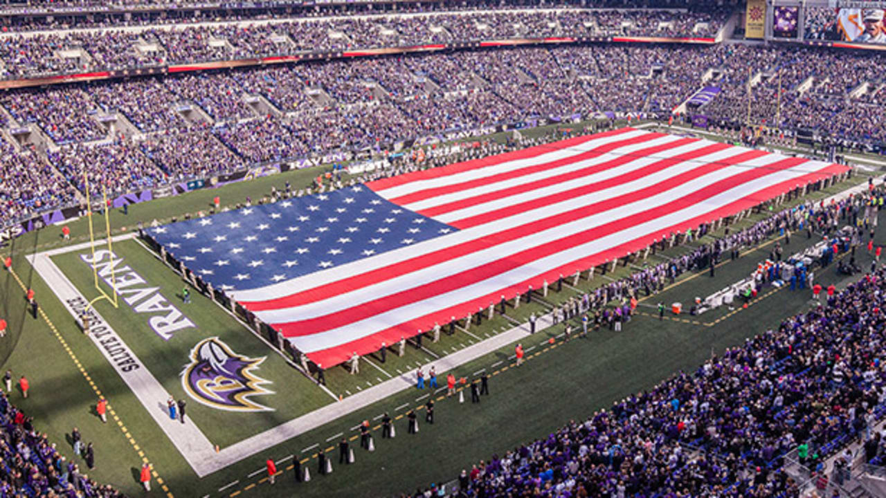 U.S. service members hold a large flag on the field at M&T Bank Stadium as  part of the Baltimore Ravens' Salute to Service prior to an NFL football  game against the Houston Texans, Sunday, Nov. 17, 2019, in Baltimore. (AP  Photo/Julio Cortez Stock Photo