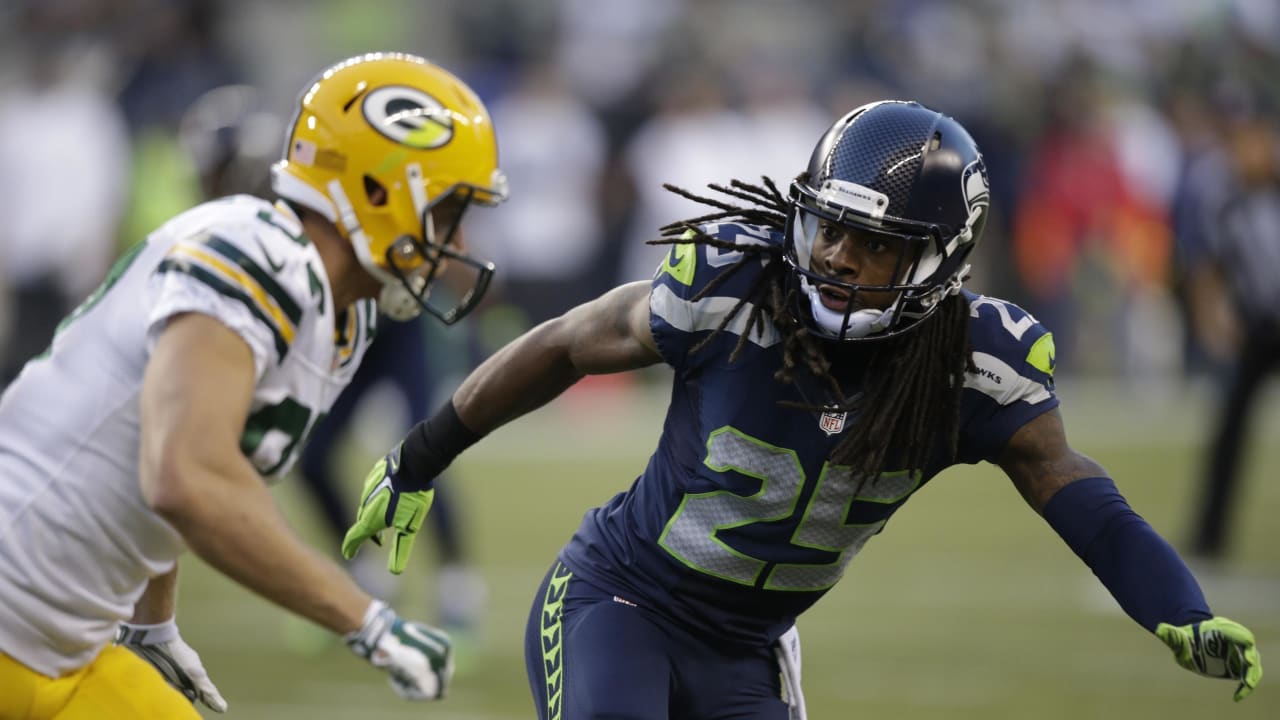 Michael Bennett (72) of the Seattle Seahawks loses his helmet as he tackles  Eddie Lacy (27) of the Green Bay Packers in the NFC Championship game at  CenturyLink Field in Seattle, Washington