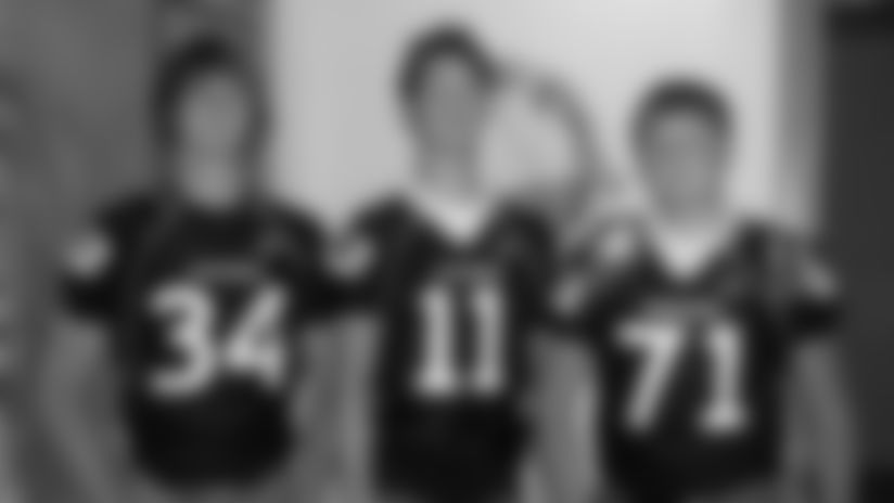 Austin (center) and Dalton (right) pose for a photo in their Wiggins football uniforms.