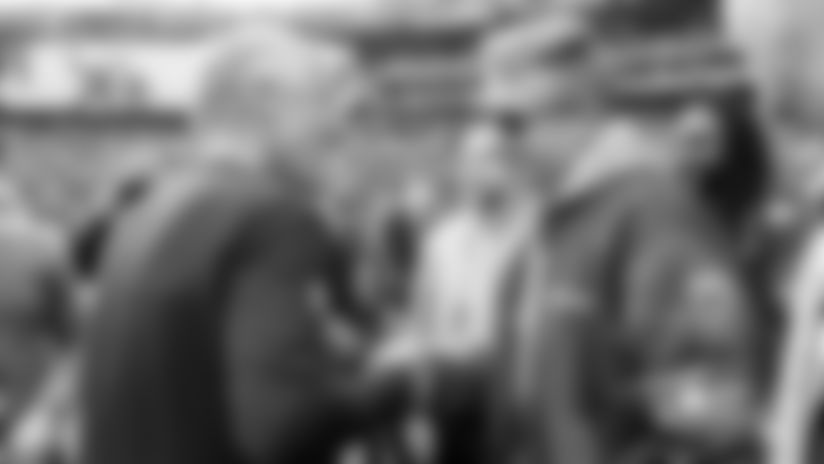 Pete Carroll greets Macklemore on the sidelines during warmups.