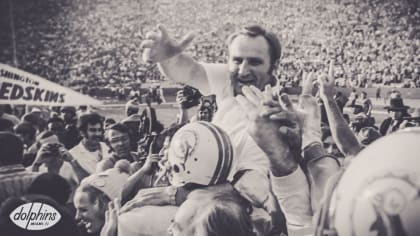 Mary Anne Shula hugs Tom Garfinkle, President and CEO of the Miami  Dolphins, during a ceremony honoring former head coach Don Shula during  half time of an NFL football game against the