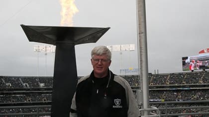 Former Raider tight end Dave Casper stands with a signed jersey, a bottle  of Robert Mondovi Wine . a guitar and a famous Herman Miller Alron Chair,  all part of a fundrainser