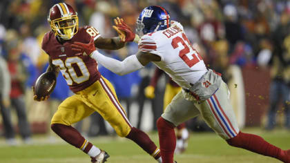 Los Angeles running back Marcus Allen (32) tries to break away from  Washington Redskins Dave Butz (65) as Rich Milot (57) looks on during the  first half of their game at R.F.K.