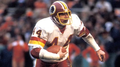 Los Angeles running back Marcus Allen (32) tries to break away from  Washington Redskins Dave Butz (65) as Rich Milot (57) looks on during the  first half of their game at R.F.K.