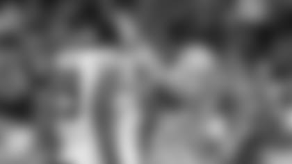 Longtime Bears assistant equipment manager Carl Piekarski cleaning defensive lineman Trevis Gipson's visor