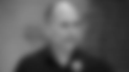 General Manager Eric DeCosta speaking at a podium.