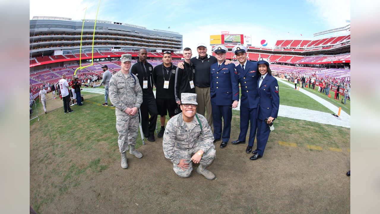 Service members from all five branches of the armed services carry a large  American flag out onto the field at the Salute to Service Chicago Bears  game Nov. 27 at Soldier Field