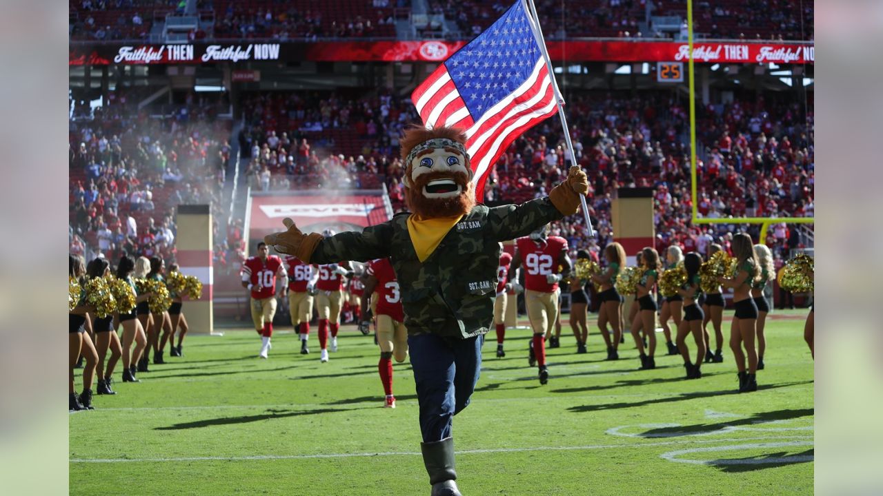 Fans hold up red, white and blue cards in a Salute to Service as the flag  is presented during the national anthem before an NFL football game between  the San Francisco 49ers