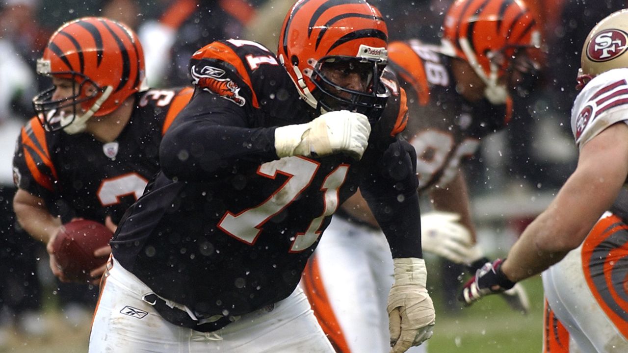 Former Cincinnati Bengals player Willie Anderson, left, signs