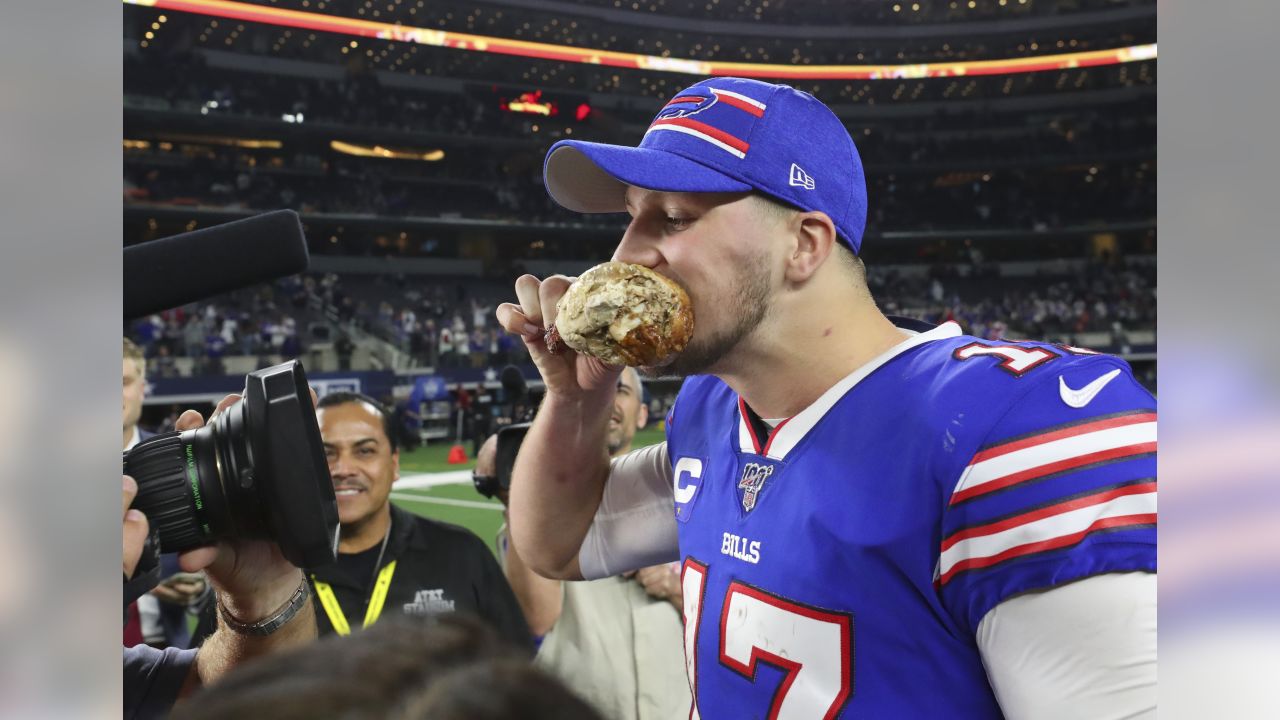 Josh Allen of the Buffalo Bills eats a turkey leg while he walks off