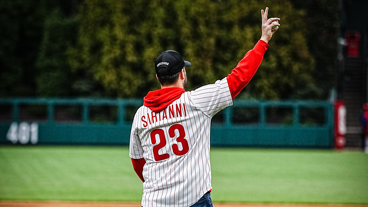 Philadelphia Phillies - Nick Sirianni throwing the first pitch before the  game at Citizens Bank Park. He's got a smile on his face. He's wearing a  red pinstripes Phillies jersey, a red