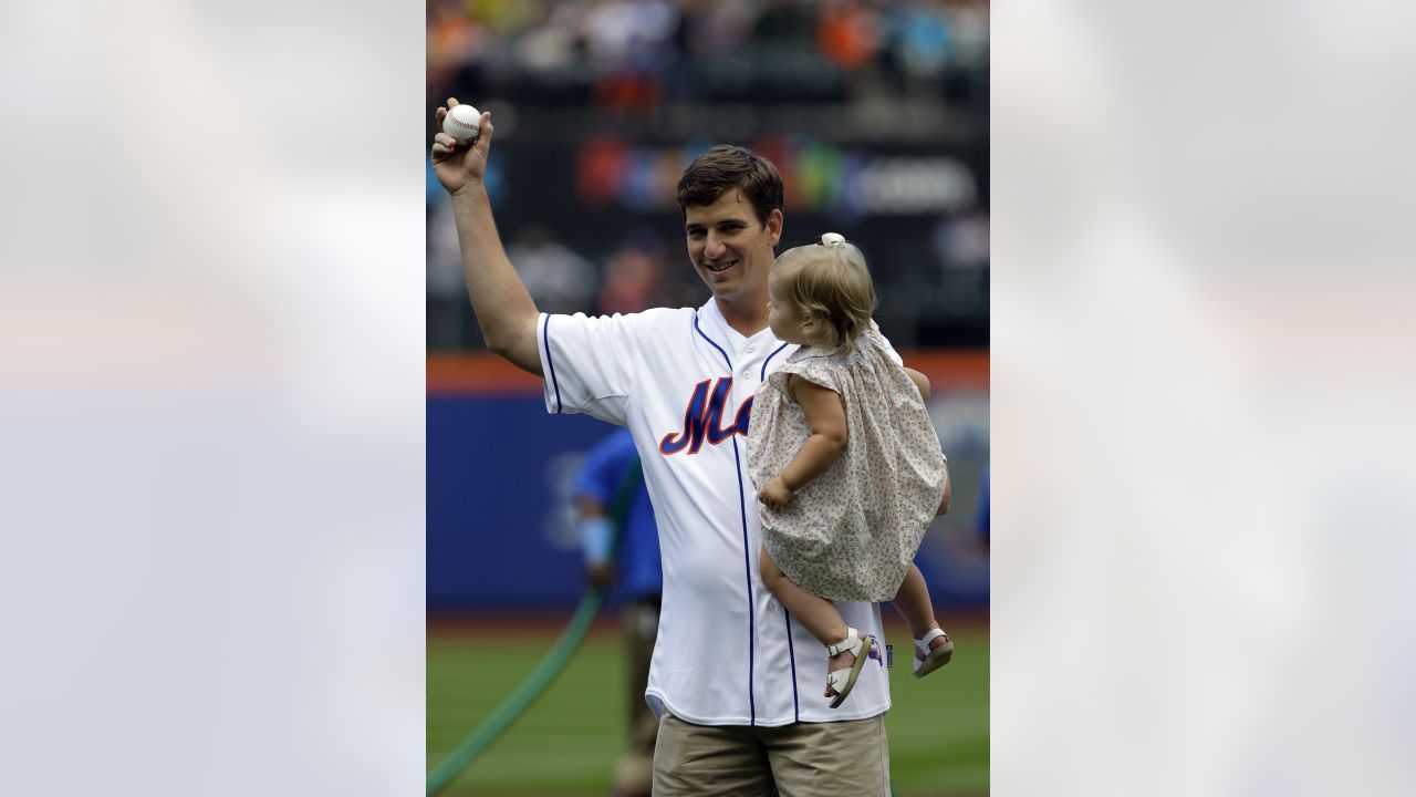 New York Giants quarterback Eli Manning, right, holds his daughter Ava as  he chats with New York Mets third baseman David Wright, left, after  throwing out the ceremonial first pitch on Father's