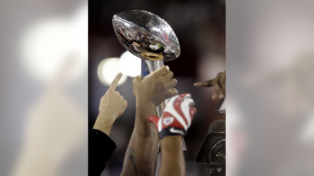 New York Giants wide receiver Devin Thomas, center, holds the Vince Lombari  trophy while teammates celebrate after defeating the New England Patriots  21-17 to win Super Bowl XLVI February 5, 2012, in