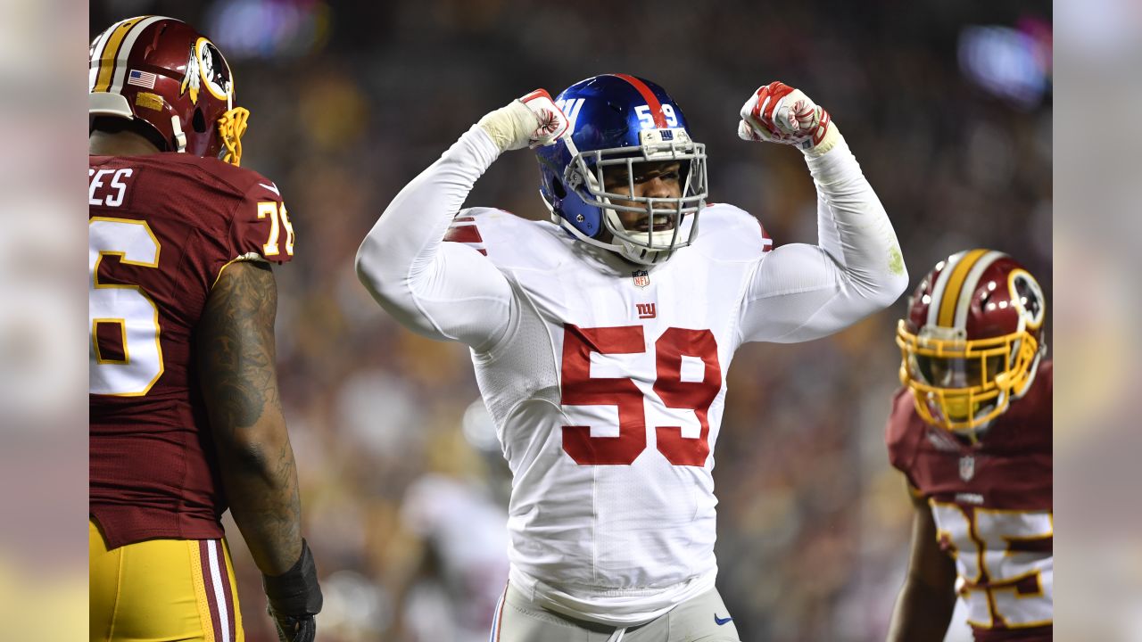 Washington Redskins Vs. New York Giants. NFL Game. American Football League  Match. Silhouette Of Professional Player With Open Arms, Who Holds Ball In  Hands. Screen In Background. Stock Photo, Picture and Royalty