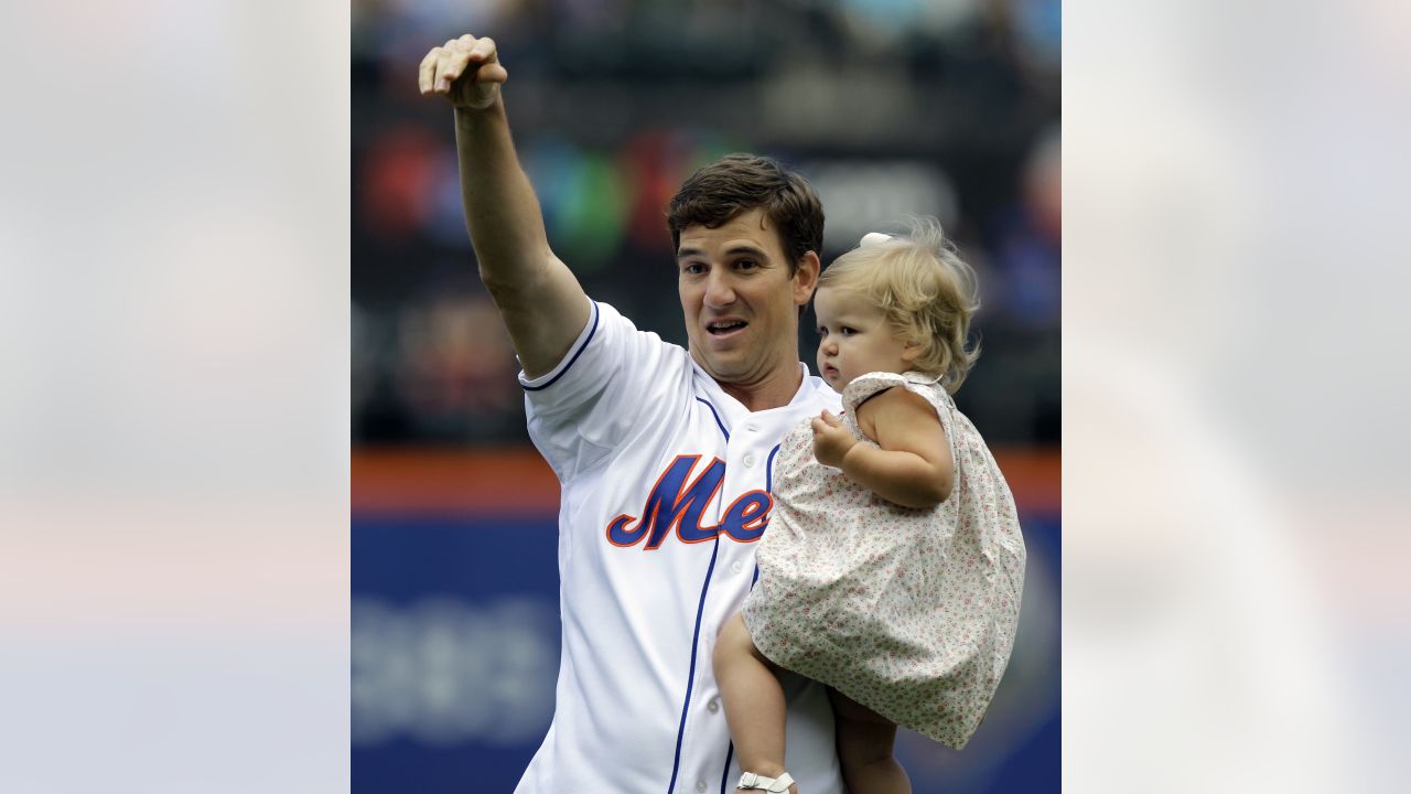 New York Giants quarterback Eli Manning, left, holds daughter Ava as he  stands with New York Mets third baseman David Wright after Wright caught  his ceremonial first pitch before a baseball game