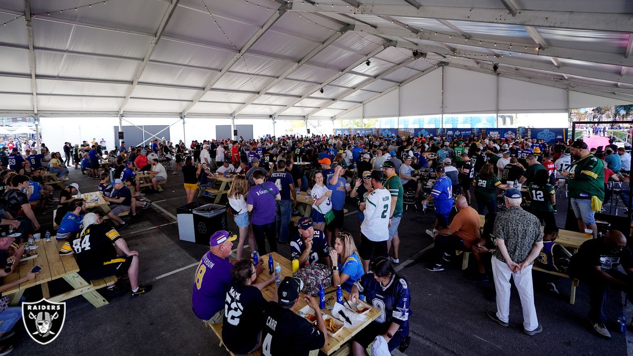 A crowd gathers to watch the start of the 2022 NFL Draft from the Draft  Theater as a military f …