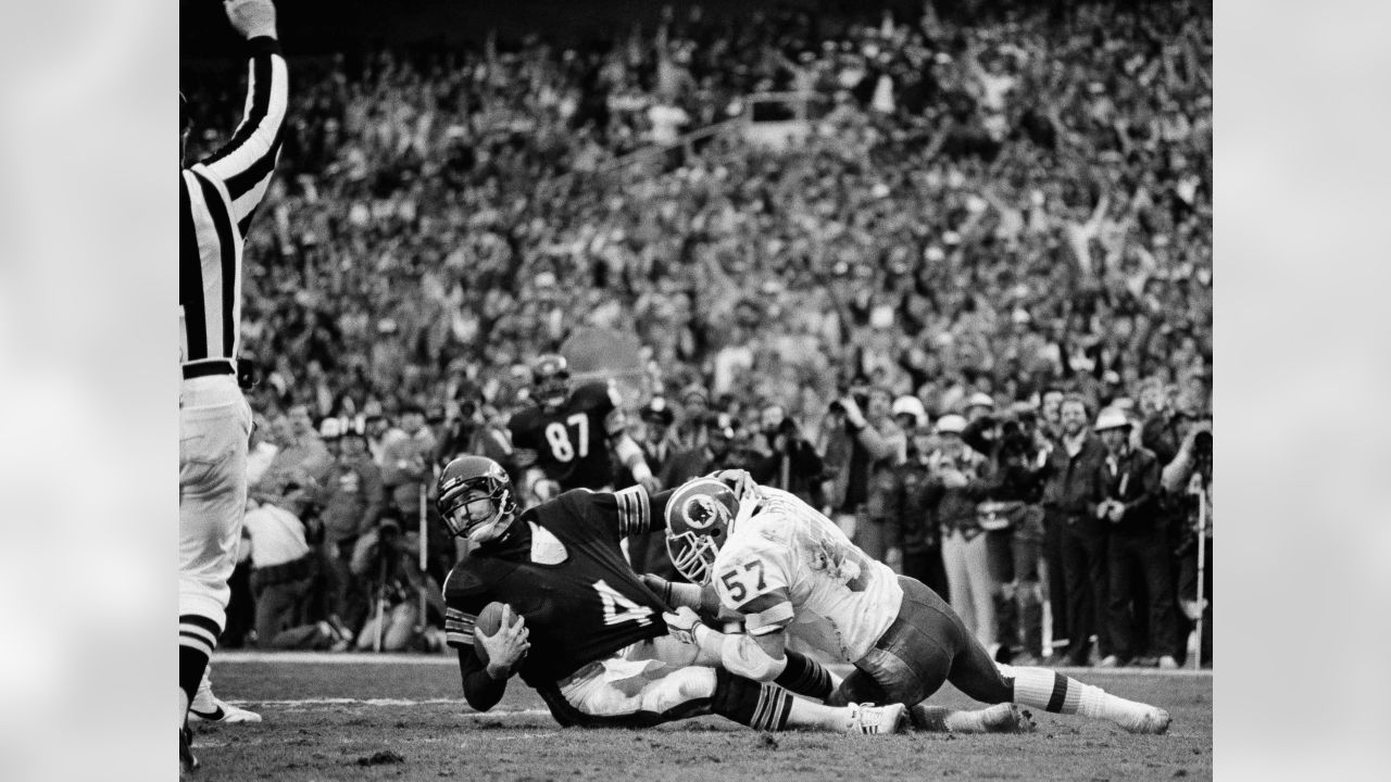 Los Angeles running back Marcus Allen (32) tries to break away from  Washington Redskins Dave Butz (65) as Rich Milot (57) looks on during the  first half of their game at R.F.K.