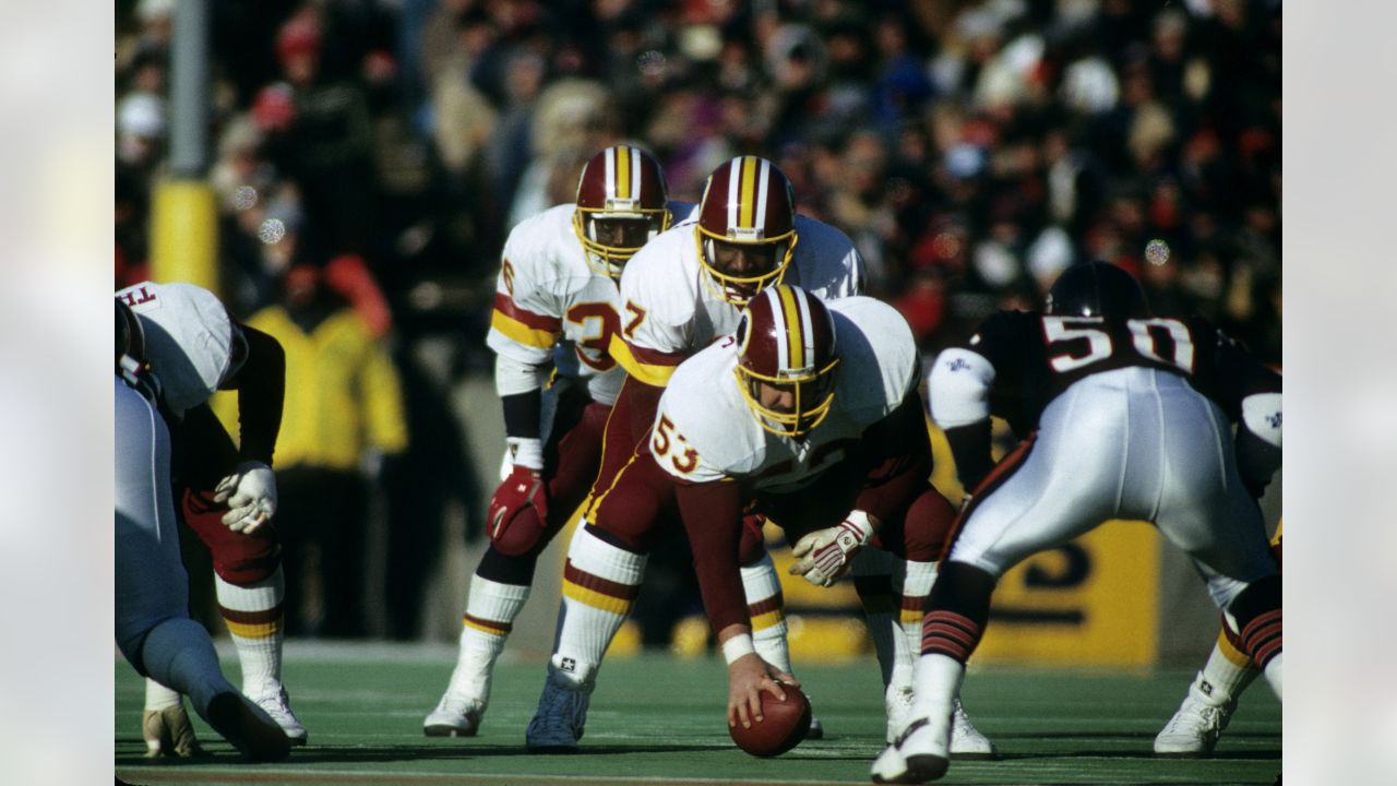 Los Angeles running back Marcus Allen (32) tries to break away from  Washington Redskins Dave Butz (65) as Rich Milot (57) looks on during the  first half of their game at R.F.K.