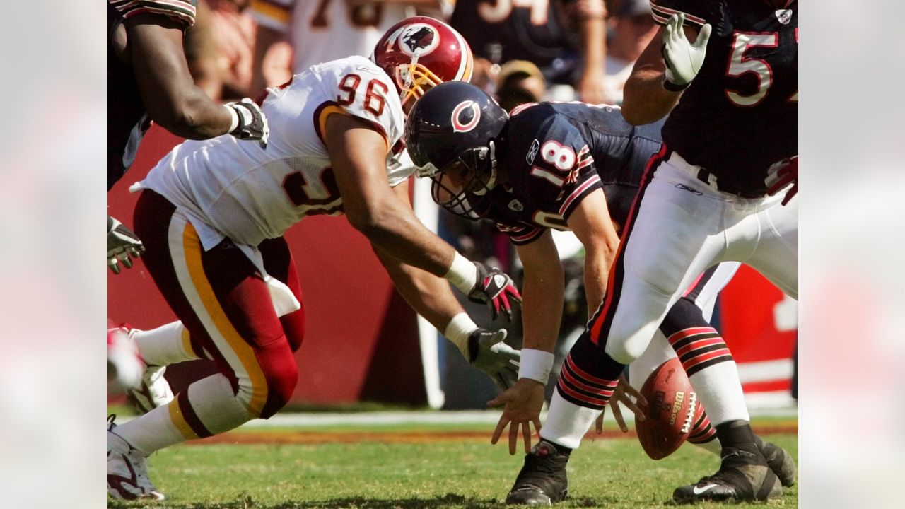 Los Angeles running back Marcus Allen (32) tries to break away from  Washington Redskins Dave Butz (65) as Rich Milot (57) looks on during the  first half of their game at R.F.K.