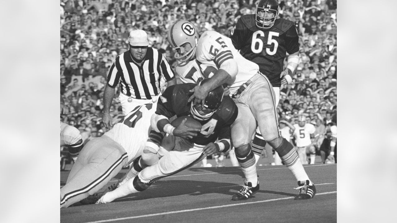 Los Angeles running back Marcus Allen (32) tries to break away from  Washington Redskins Dave Butz (65) as Rich Milot (57) looks on during the  first half of their game at R.F.K.