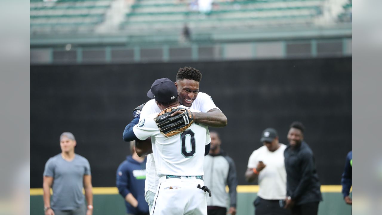 Seattle Seahawks rookie wide receiver DK Metcalf throws out the first pitch  at a baseball game between the Seattle Mariners and the Baltimore Orioles,  as other rookies from the NFL football team