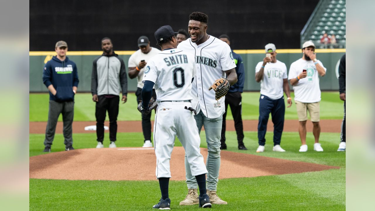 Seattle Seahawks rookie wide receiver DK Metcalf throws out the first pitch  at a baseball game between the Seattle Mariners and the Baltimore Orioles,  as other rookies from the NFL football team