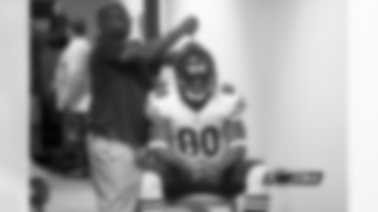Head equipment manager Tony Medlin tightens Earl Bennett's helmet in the Bears locker room.