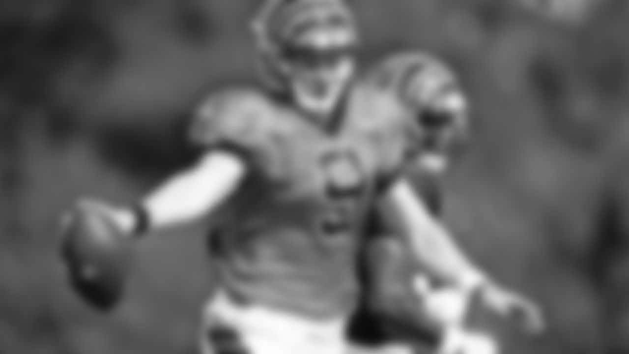 Quarterback Joe Burrow holds the ball out to reach for a first down during the team's first scrimmage.