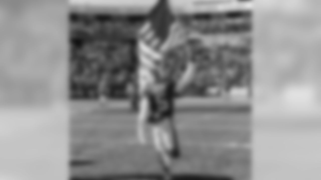 Buffalo Bills quarterback Tyrod Taylor runs on the field on Salute to Service gameday 2015, while holding the American flag.