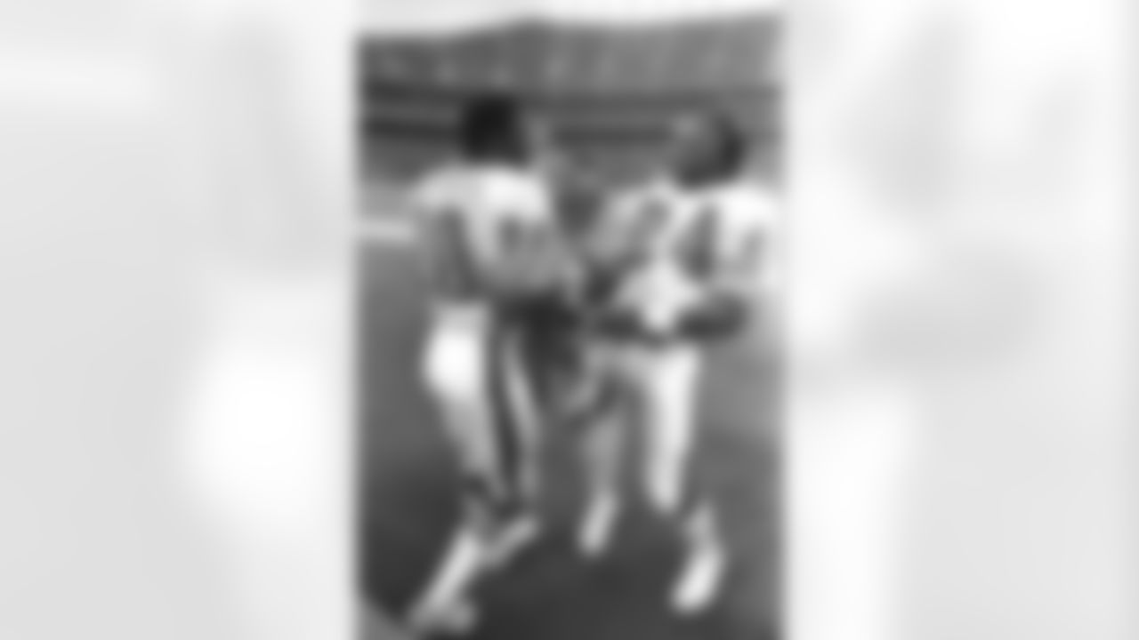 Rick Upchurch and Otis Armstrong laugh on the sideline.