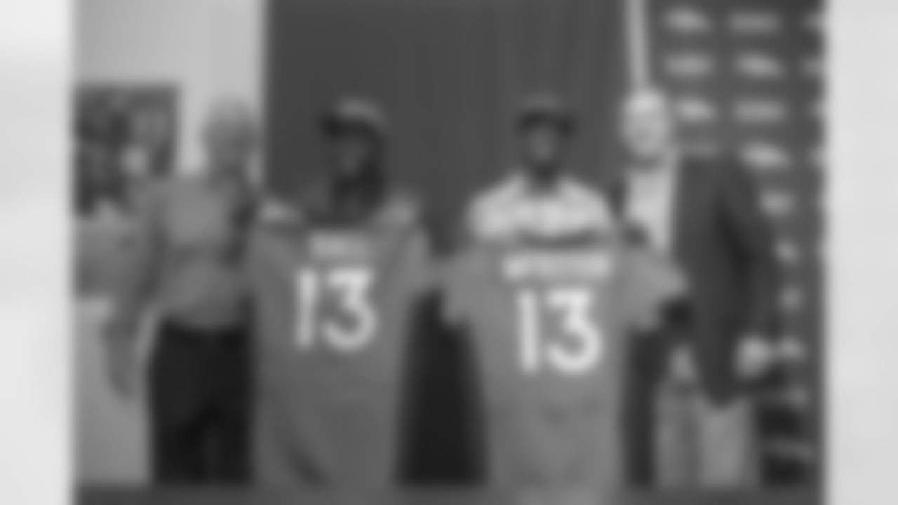 The pair of draftees show Denver media their jerseys.