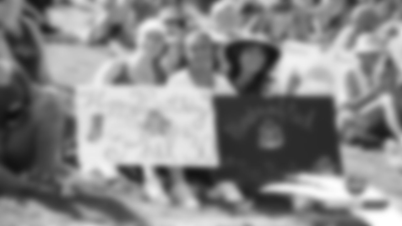Fans hold up signs celebrating Phillip Lindsay's birthday during practice on Day 6 of training camp on July 24, 2019.