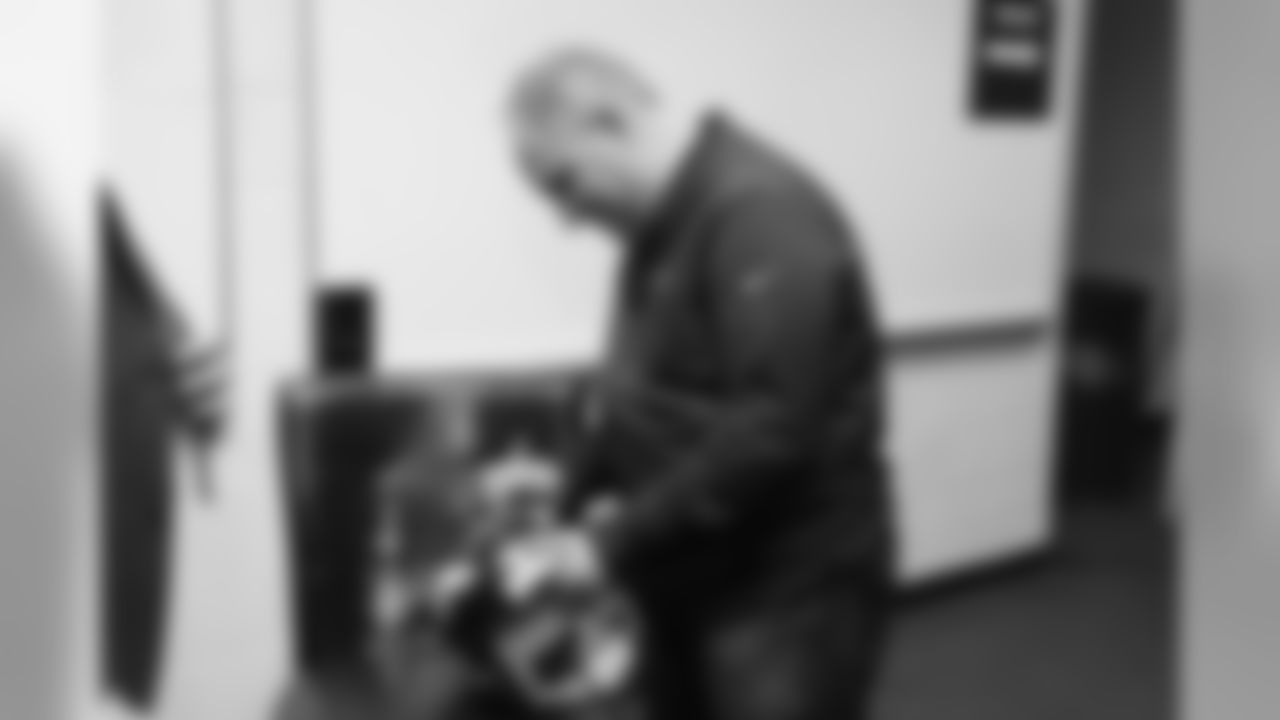 Head Coach Vic Fangio autographs a helmet for a raffle at a meet-and-greet visit with team employees at Broncos Stadium at Mile High on March 19, 2019.