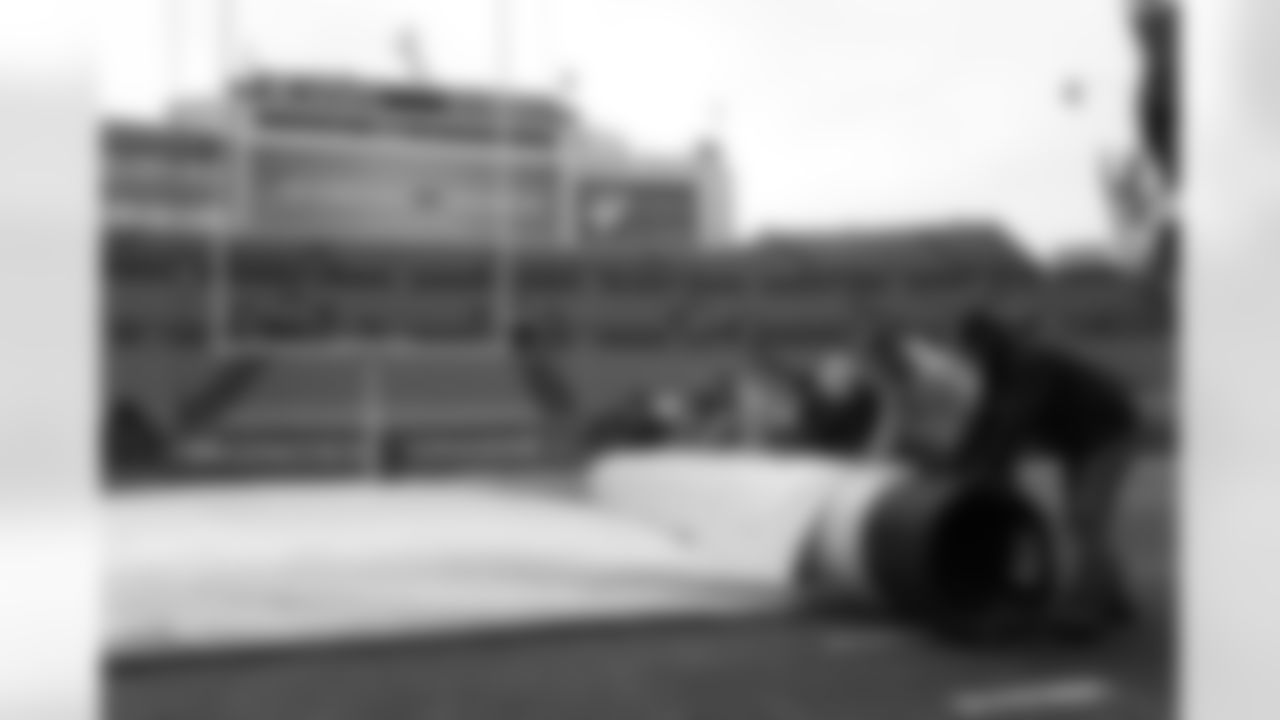 The grounds crew removes the tarp from the playing field.