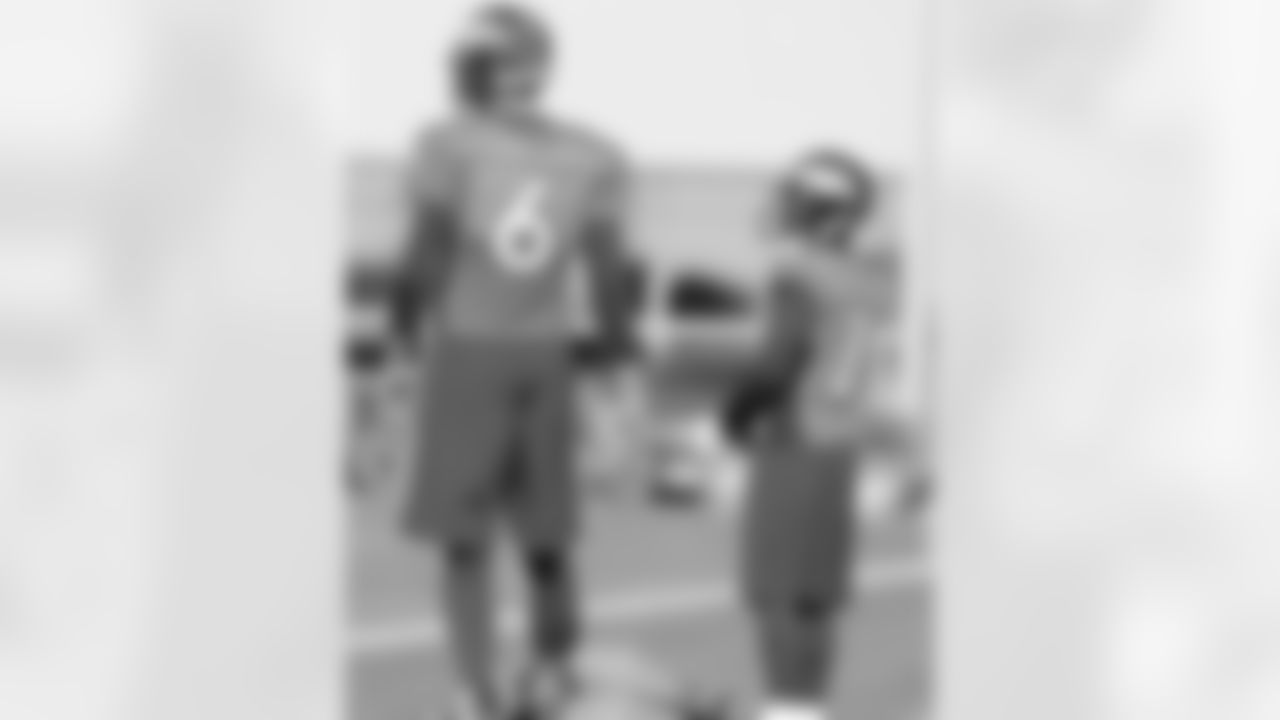 The tallest (6-8) and shortest (5-5) players in Broncos history watch a drill.