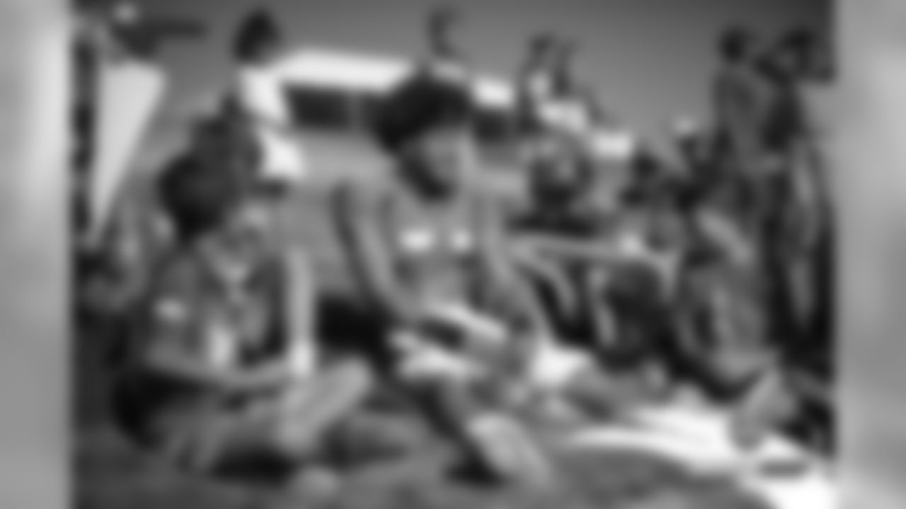 Phillip Lindsay sits with some young fans before practice on Day 16 of training camp on August 12, 2019.