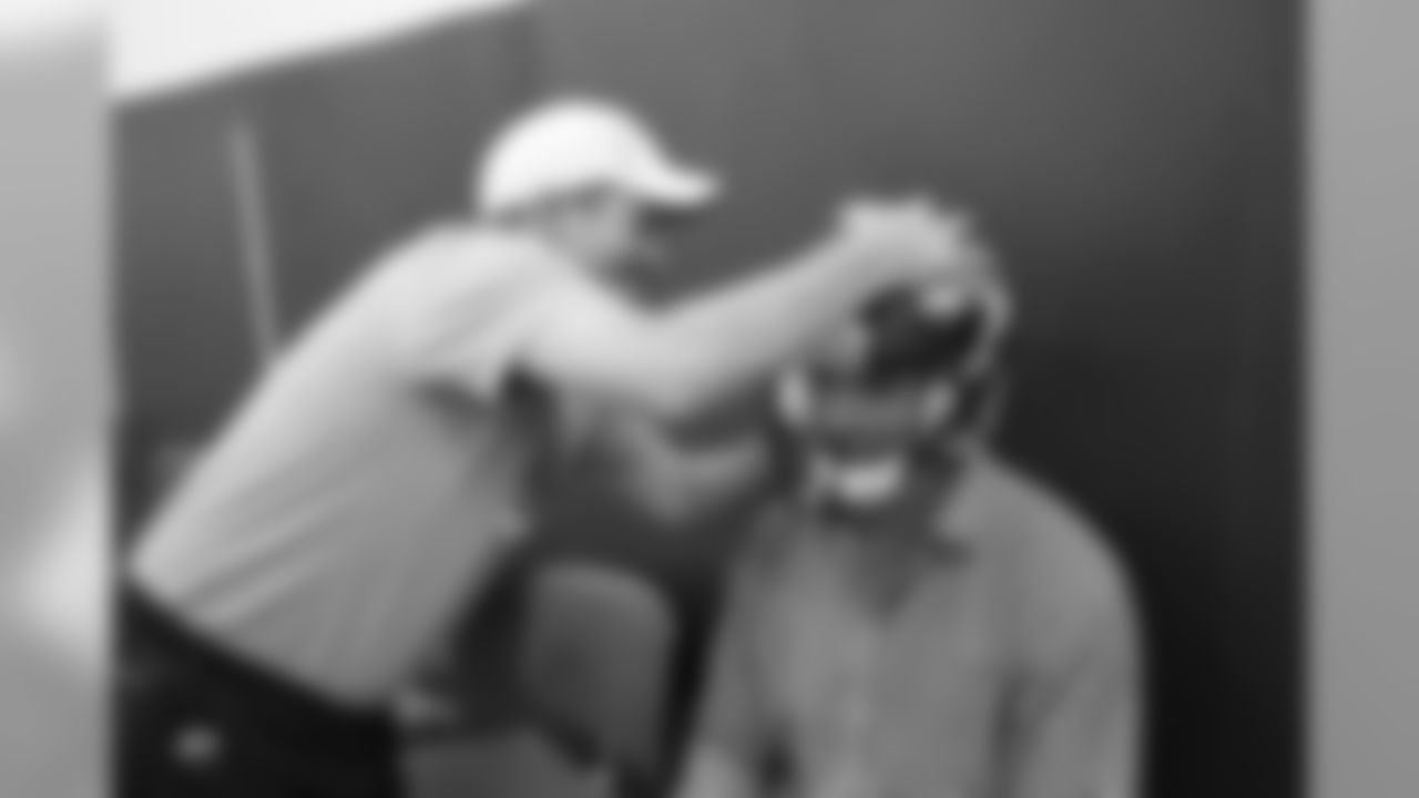 Equipment manager Chris Valenti had the 6-7 QB Brock Osweiler sit down while adjusting his helmet.