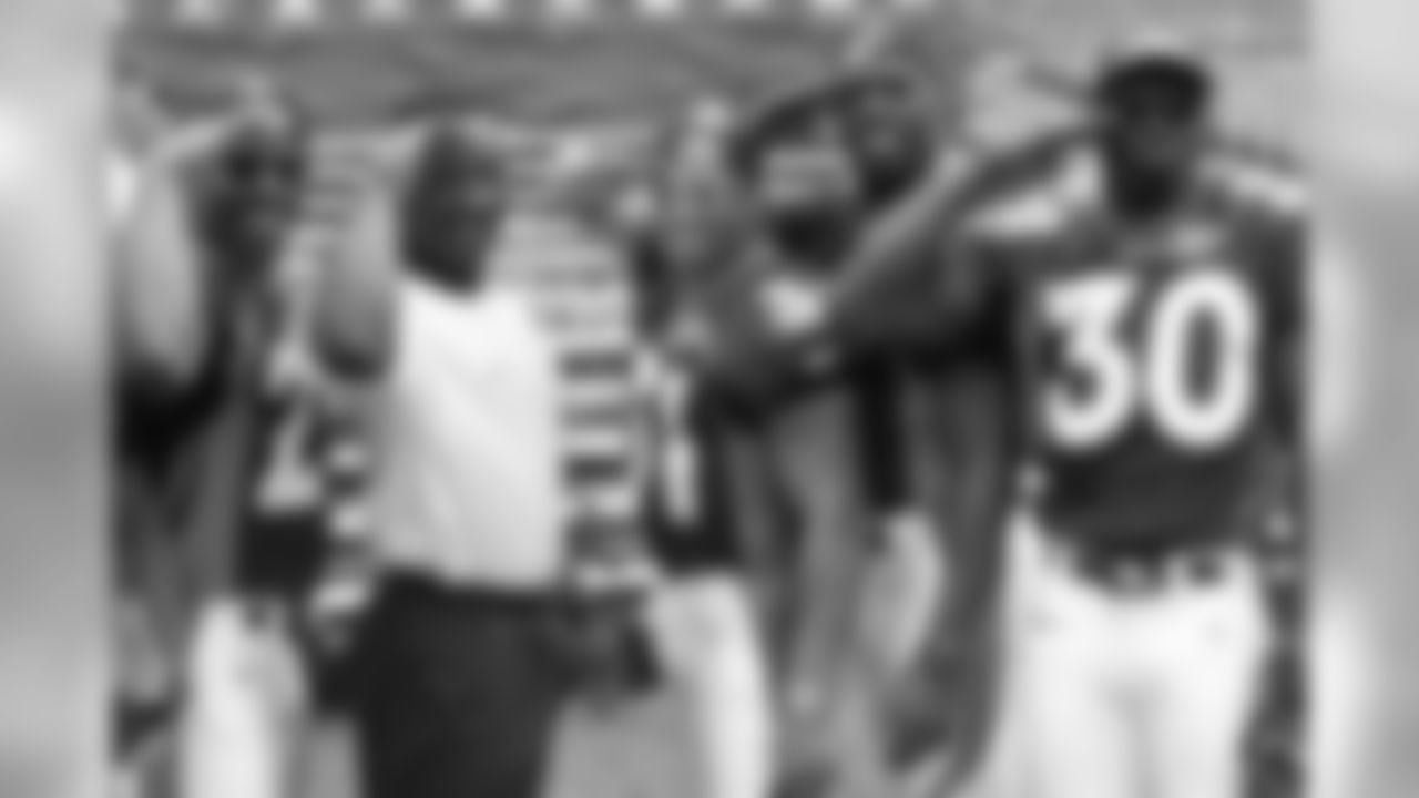 Denver Broncos running back Howard Griffith (29), coach Bobby Turner, running backs Derek Loville (31), Anthony Lynn (37) and Hall of Fame running back Terrell Davis (30) give Mile High Salutes as they pose for a photo during the NFL Super Bowl 32 Media Day, Tuesday, Jan. 20, 1998, in San Diego. The defeated the Green Bay Packers 31-24. (Kevin Terrell via AP)