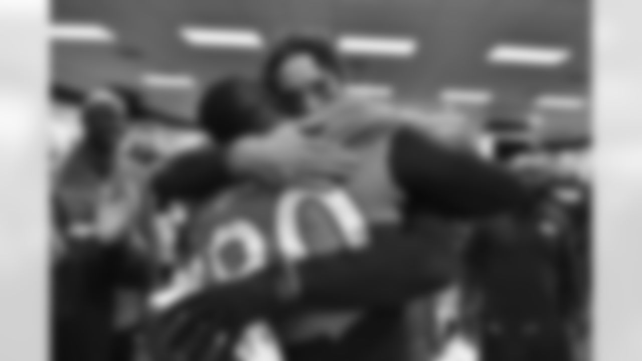 Denver Broncos quarterback Brock Osweiler (17) gets a congratulatory hug from Antonio Smith (90) postgame in the locker room after Denver defeated the New England Patriots 30-24 in the NFL game at Denver,CO. November 29, 2015. (© Eric Lars Bakke/Denver Broncos)