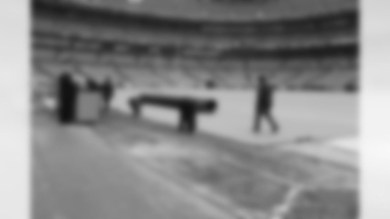 The grounds crew begins removing the tarp from the field.