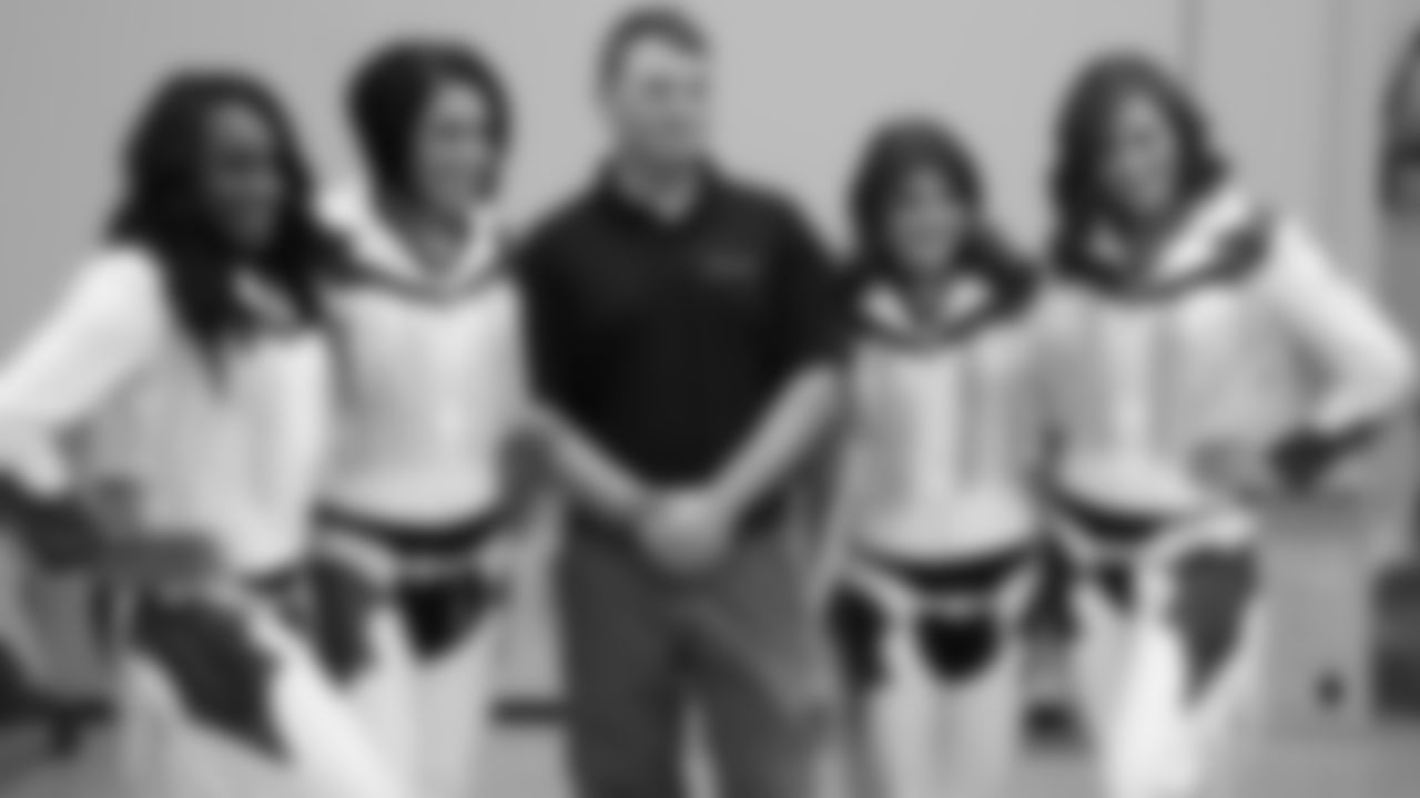Cheerleaders post with a military member during the Denver Broncos' Salute To Service Caravan at Fort Carson, Colorado on October 30, 2018.