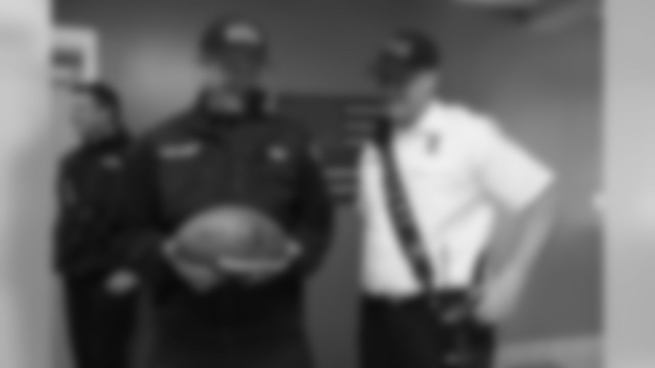 Two members of Aurora Fire Rescue look at the football autographed by Head Coach Vic Fangio during his visit for Random Acts of Kindness Week on February 20, 2019.