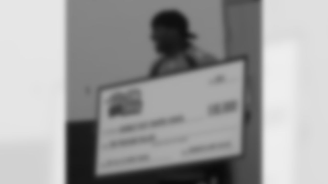 McGahee displays the Play 60 check written for Bromley East Charter School.