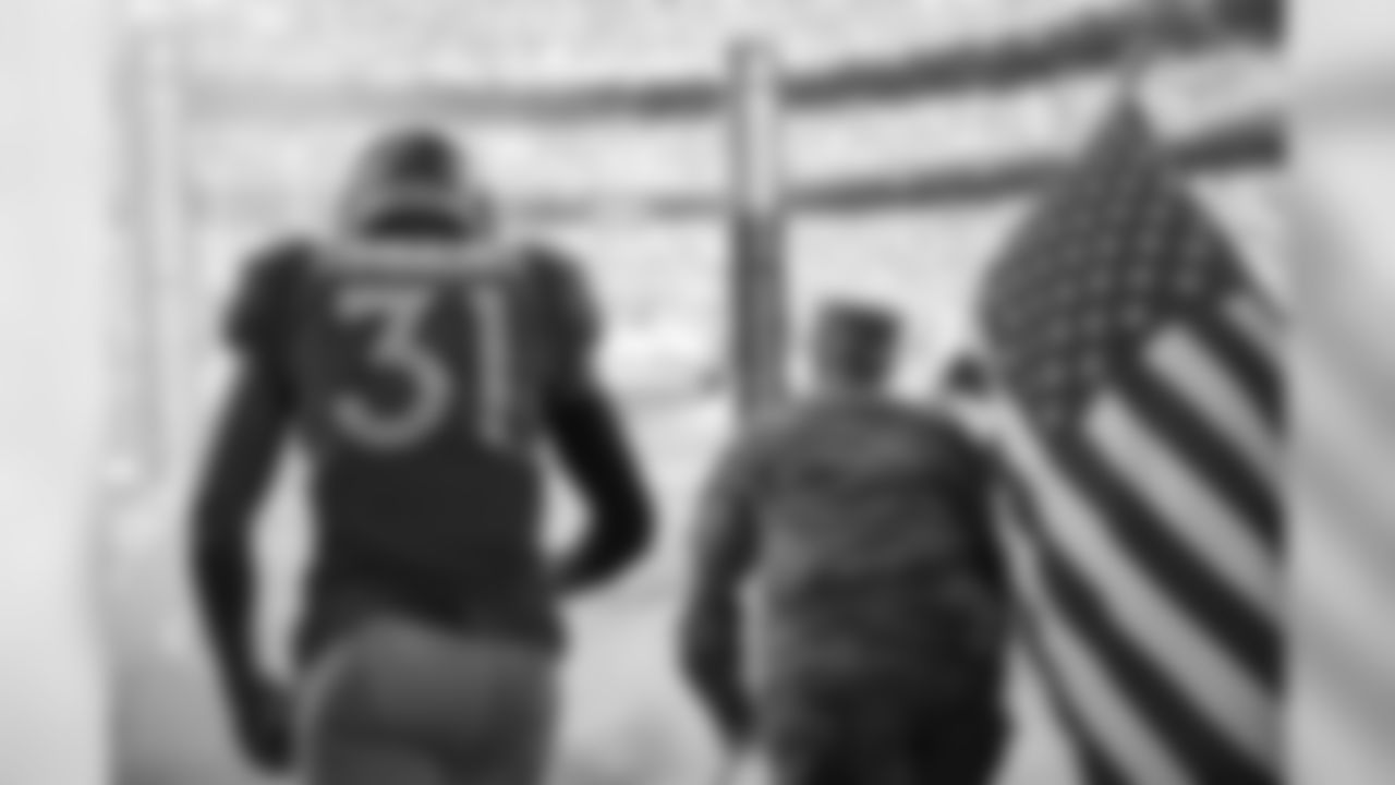 Justin Simmons and a member of the Army run out of the tunnel in the tunnel before the Broncos' game against the Cleveland Browns at Empower Field at Mile High on November 3, 2019. (Photo by Ben Swanson)