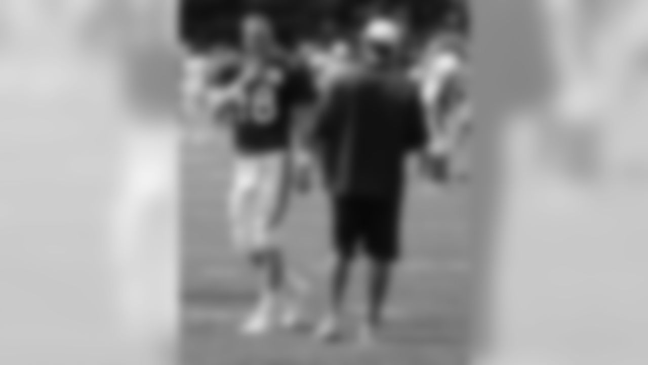Manning laughs with QB Coach Adam Gase before practice.