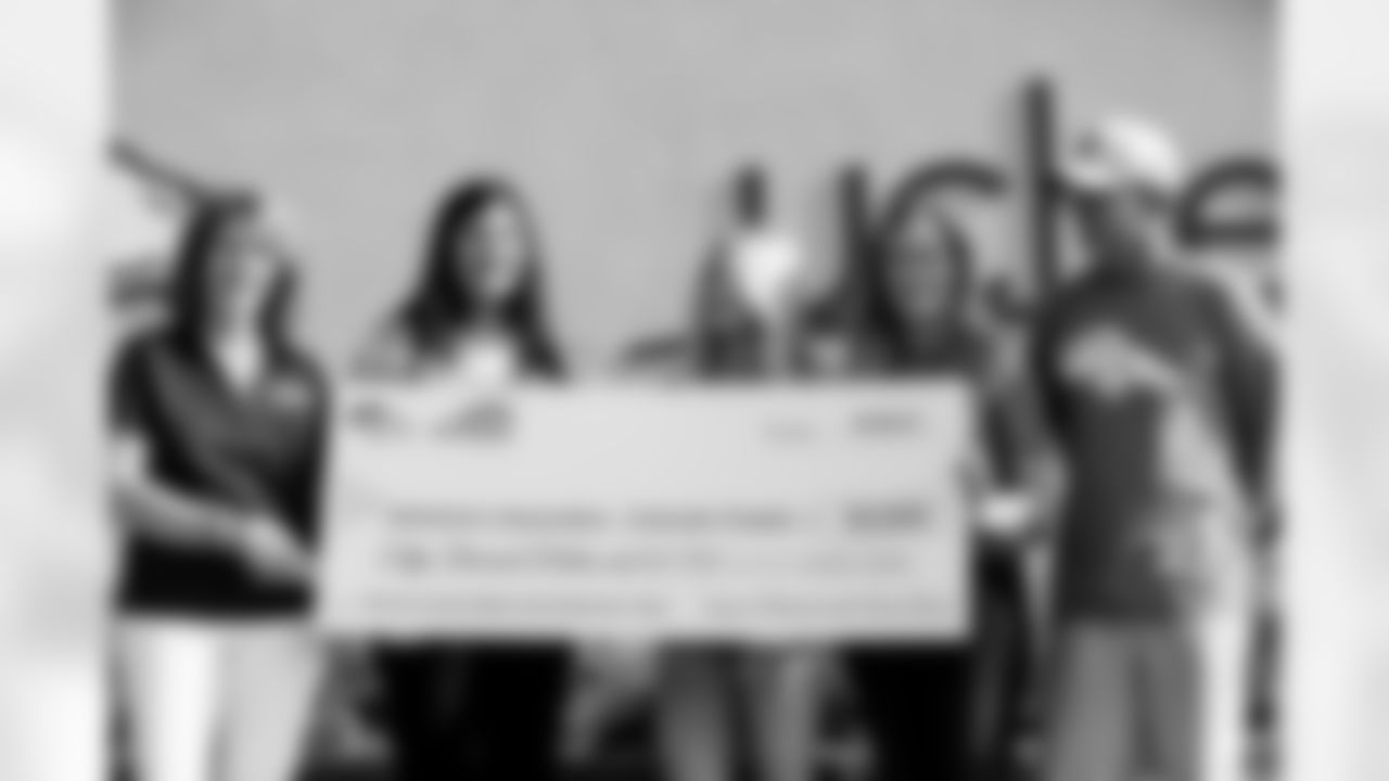 Nancy Thompson, Senior Director of Development for the Alzheimer's Association's Colorado chapter; Angie Ruddell, Empower Retirement Engagement & Corporate Social Responsibility Manager; Annabel Bowlen; Senior Vice President of Strategy Brittany Bowlen and General Manager George Paton pose for a photo with a $50,000 donation to the Alzheimer's Association's Colorado chapter during Alzheimer's Awareness Day at training camp at UCHealth Training Center on August 17, 2021. (Photo by Ben Swanson)