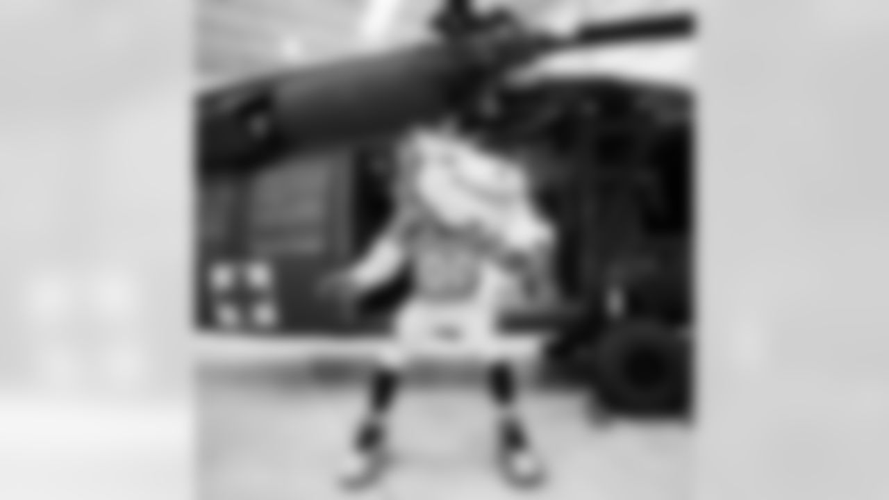 Miles the mascot slides through a helicopter door during the Salute to Service Caravan presented by USAA at Buckley Space Force Base in Aurora, Colorado on November 2, 2021. (Photo by Ben Swanson)