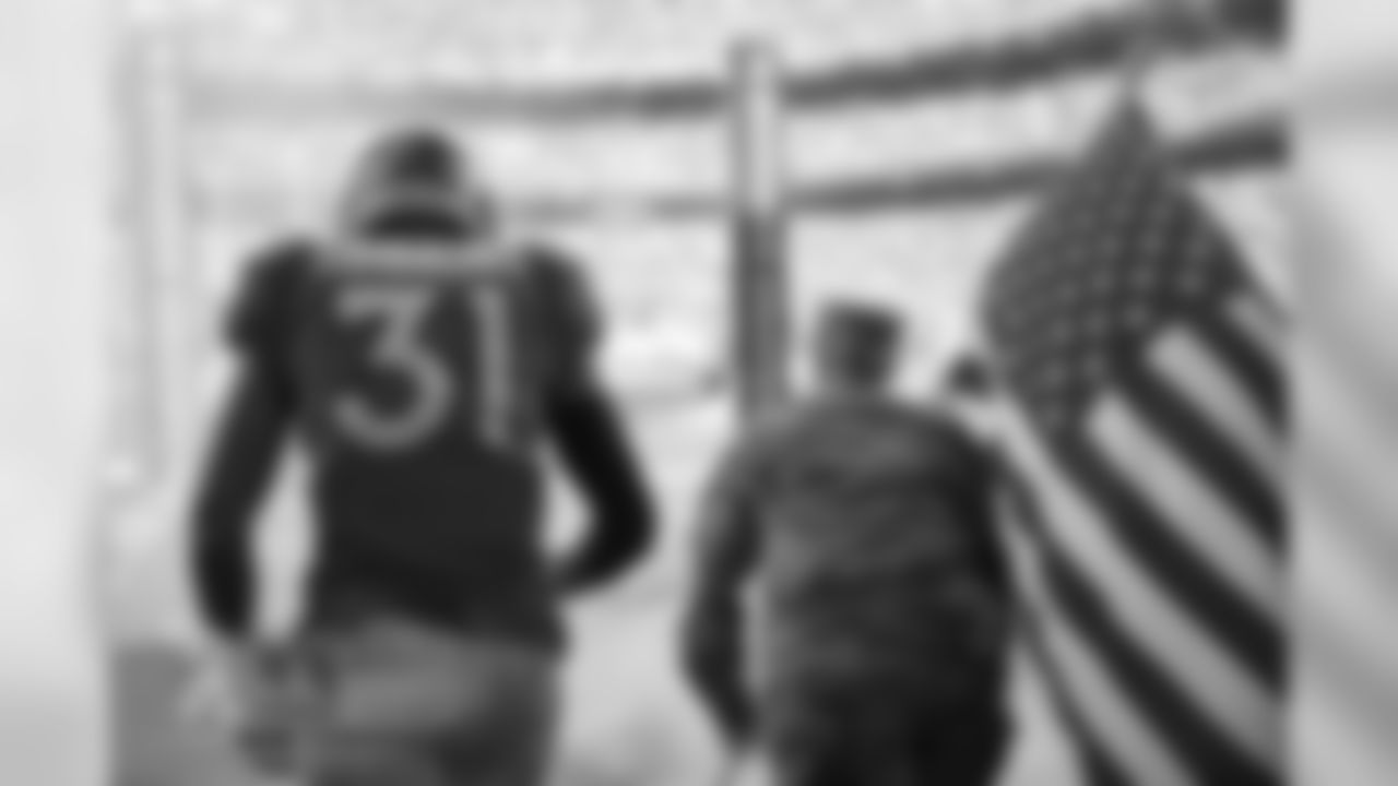 Justin Simmons and a member of the Army run out of the tunnel in the tunnel before the Broncos' game against the Cleveland Browns at Empower Field at Mile High on November 3, 2019. (Photo by Ben Swanson)