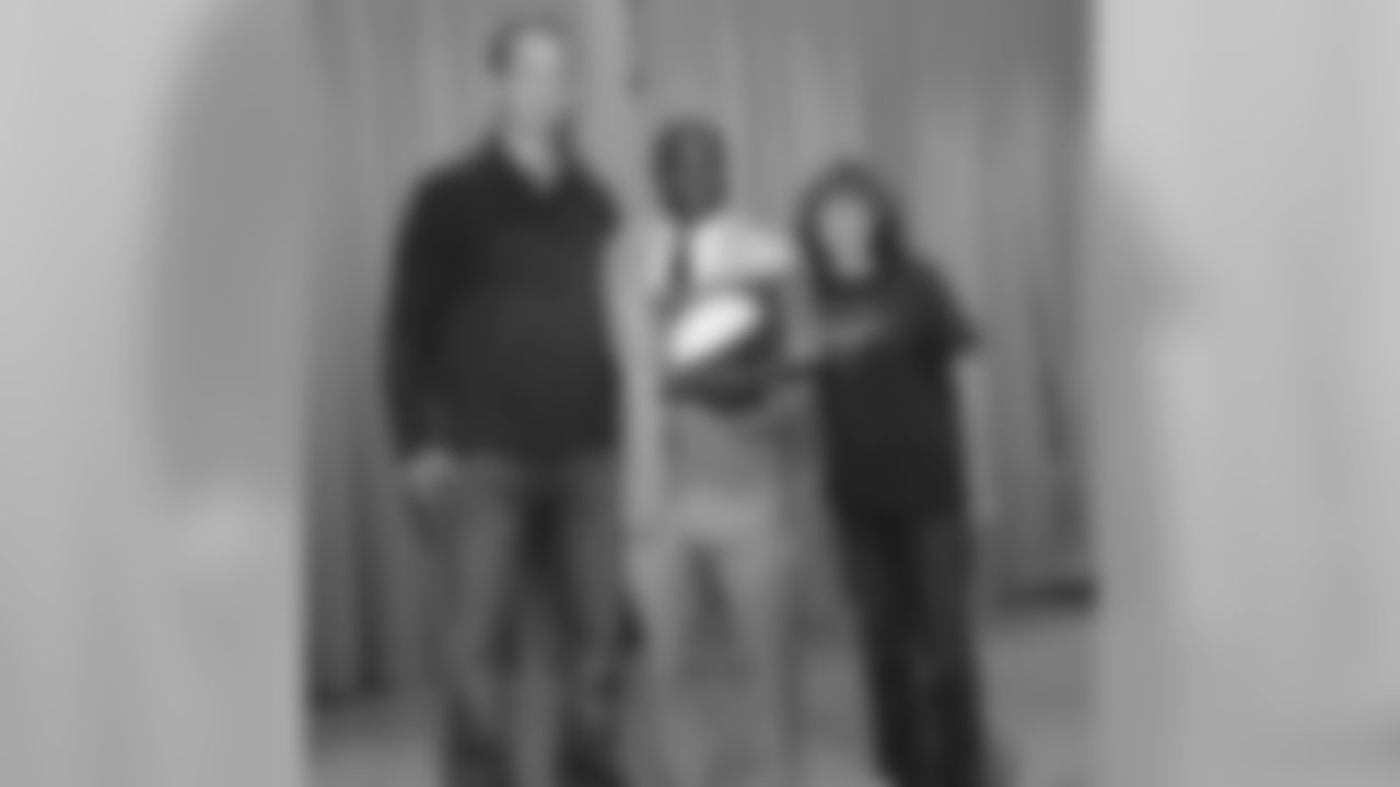 Manning presents a signed football to Principal Jai Palmer and PTA President Karen Mortimer.